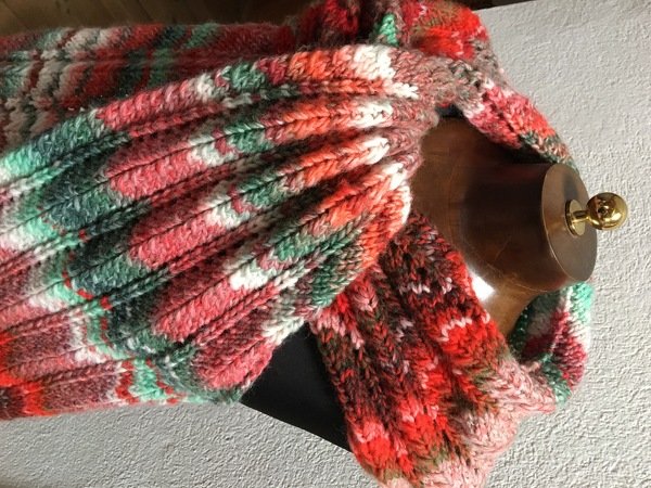 Mehrfarbiger gestrickter Schal im Rippenmuster in Rot-, Grün- und Cremetönen, lässig an einer Schaufensterpuppe drapiert