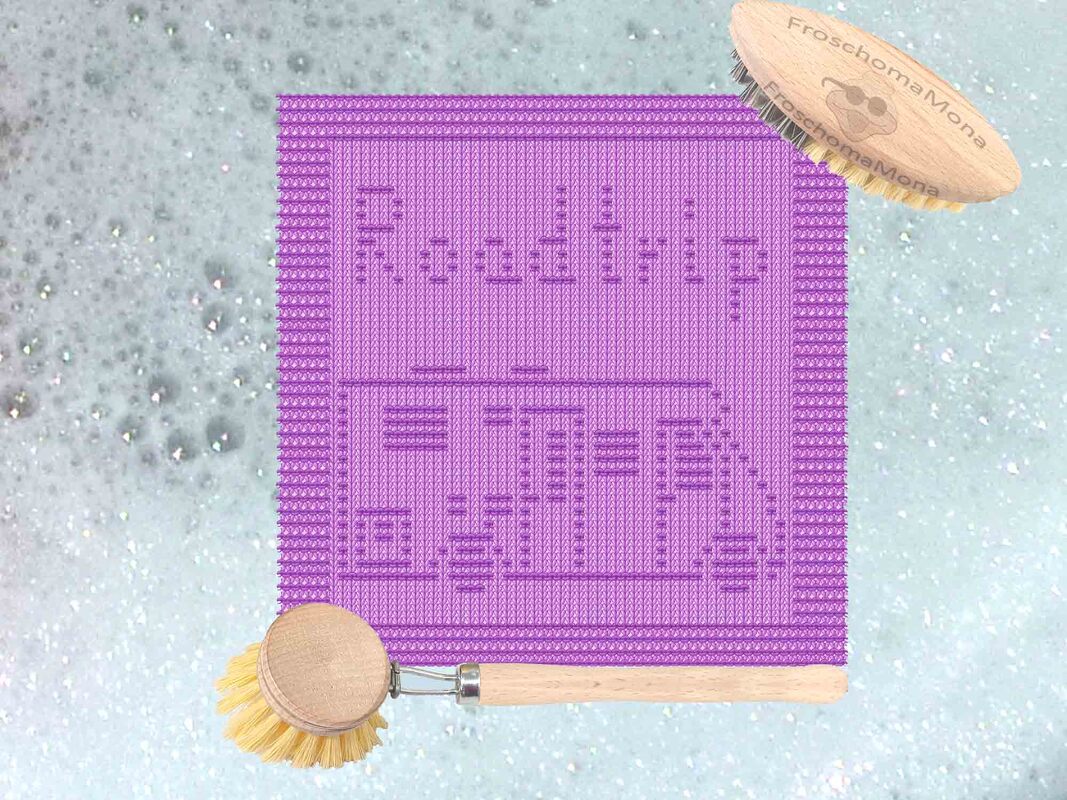 Lila gestricktes Tuch mit "Roadtrip"-Schriftzug und Wohnmobil-Motiv auf seifiger Oberfläche, neben zwei Holzbürsten aus Holz.