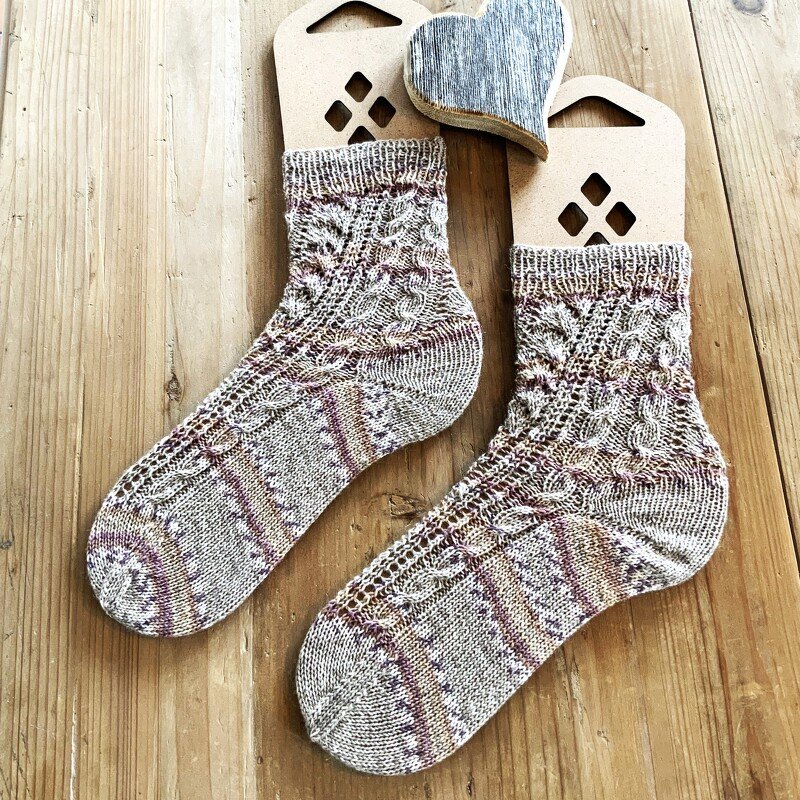 Paar gestrickte Kurzschaft-Socken in Beige- und Lilatönen mit Zopfmuster auf Holzsockenspannern