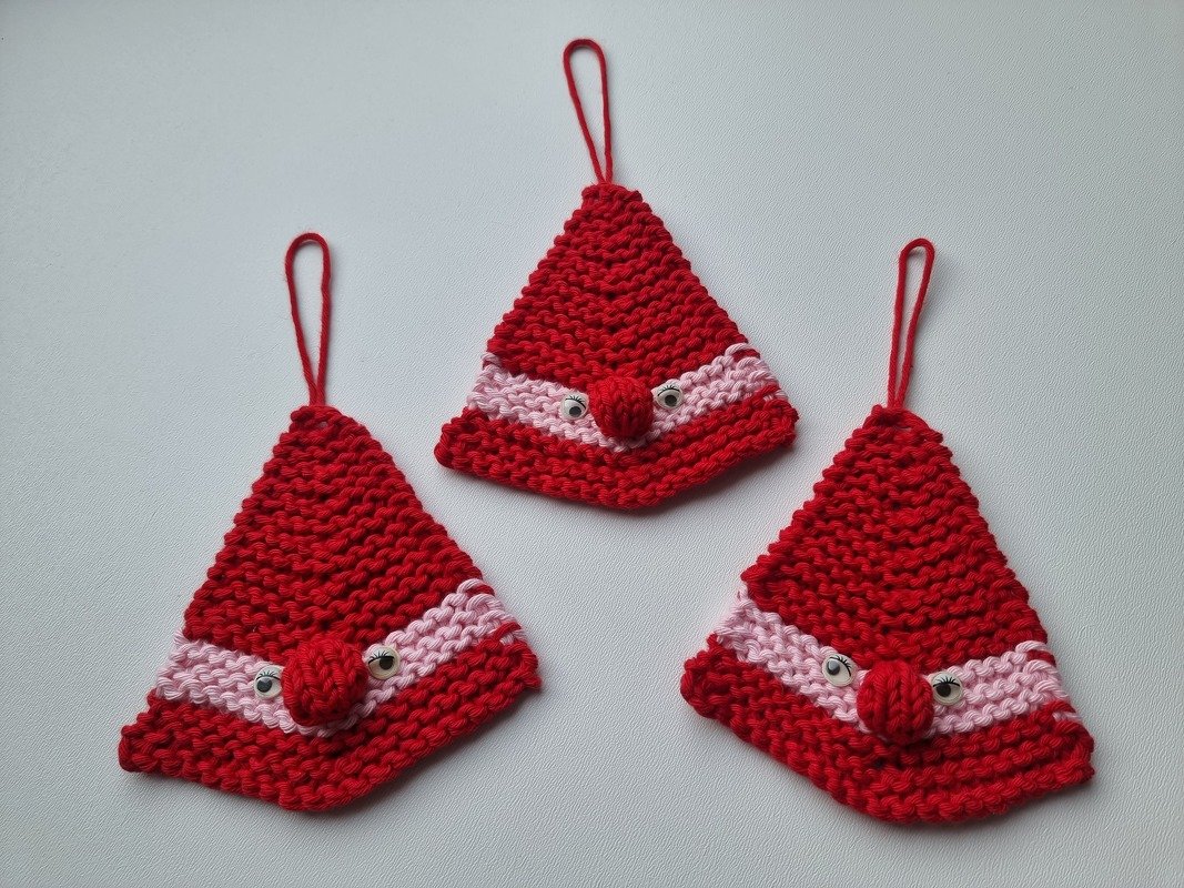 Drei gestrickte rote Wichtelmützen-Anhänger mit rosa Streifen, Knopfaugen und Aufhängeschlaufen