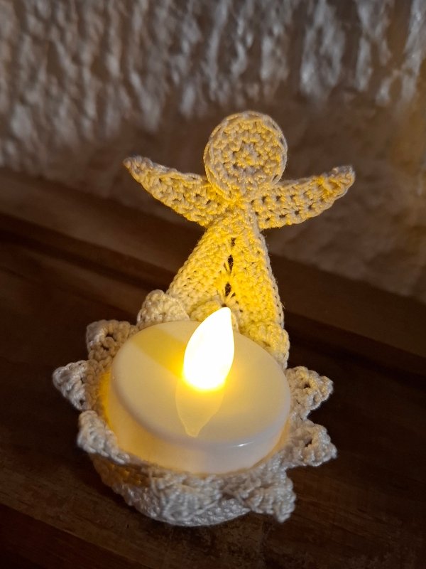 Cremefarbenes gehäkeltes Engelchen, das ein leuchtendes LED-Teelicht hält