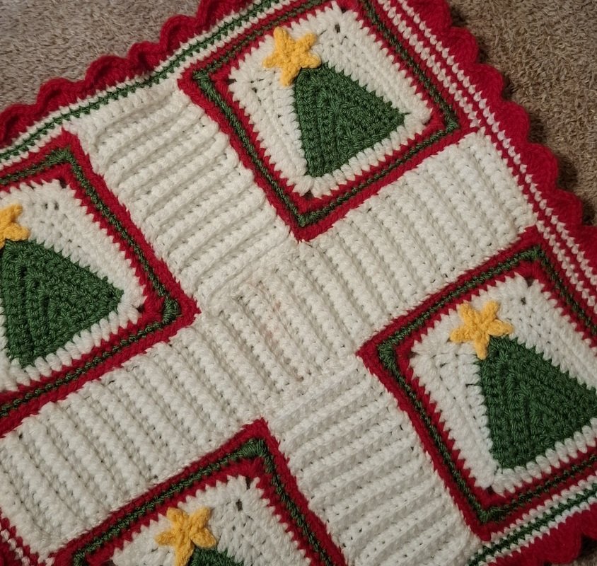 Gehäkelte Decke aus Granny Squares mit grünem Tannenbaum, gelbem Stern und roten/weißen Umrandungen