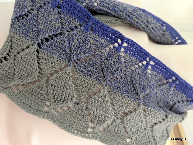 Gehäkelter Loop mit diamantförmigem Lochmuster in Grautönen und blauem Rand