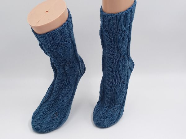 Zwei blaue gestrickte Socken mit Zopfmuster auf Schaufensterbeinen
