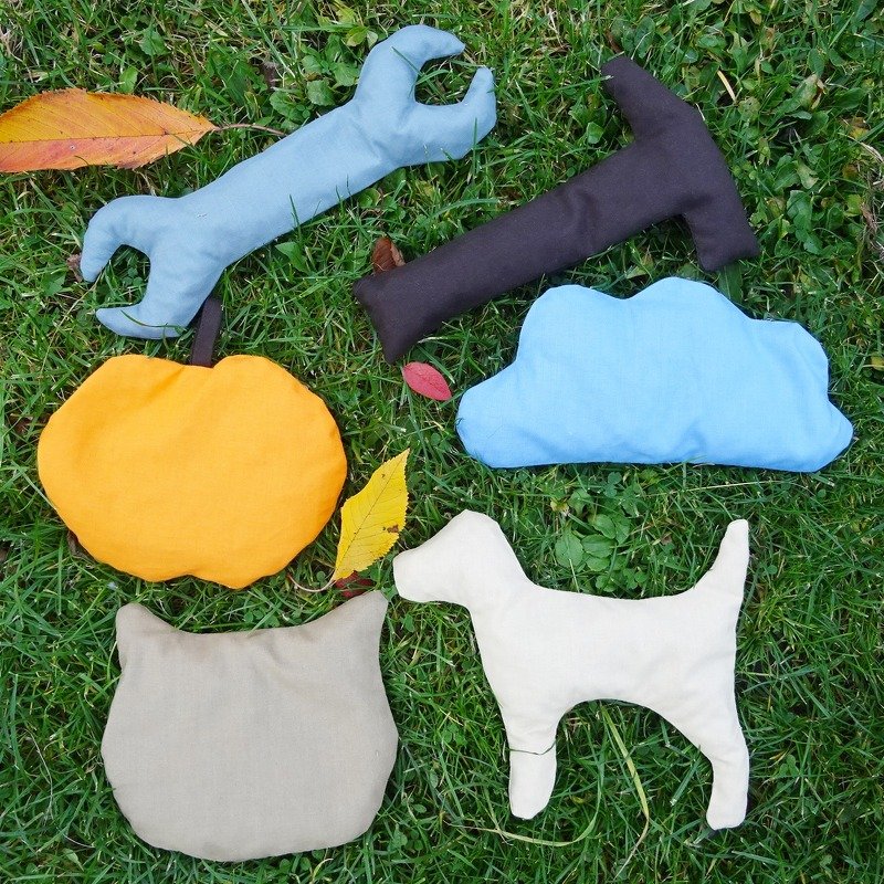 Genähte, gefüllte Stofffiguren (Schraubenschlüssel, Hammer, Wolke, Kürbis, Katzenkopf, Hund) auf Gras
