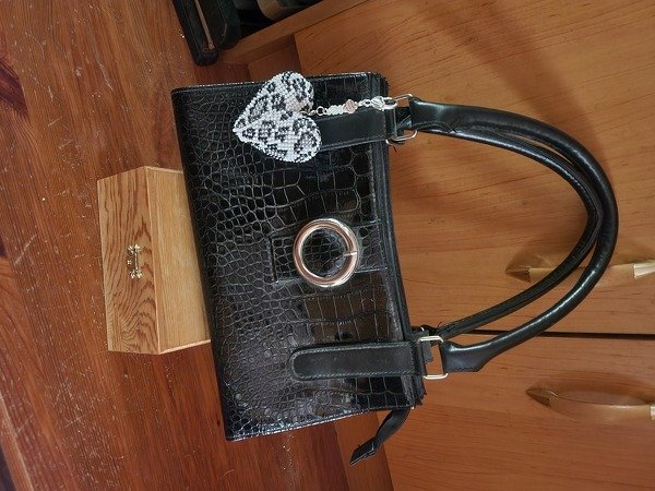 Schwarz-weißer Herzanhänger aus Rocailles an schwarzer Handtasche