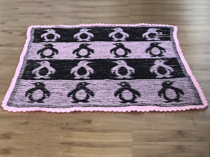 Gestrickte Decke in Schwarz und Rosa mit Pinguin-Motiv und wellenförmigem Rand