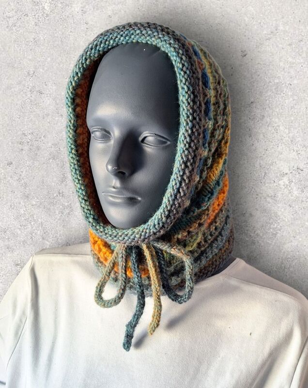 Mannequin trägt gestrickten Kapuzen-Loop in Grün-, Gelb- und Orangetönen mit gebundener Kordel