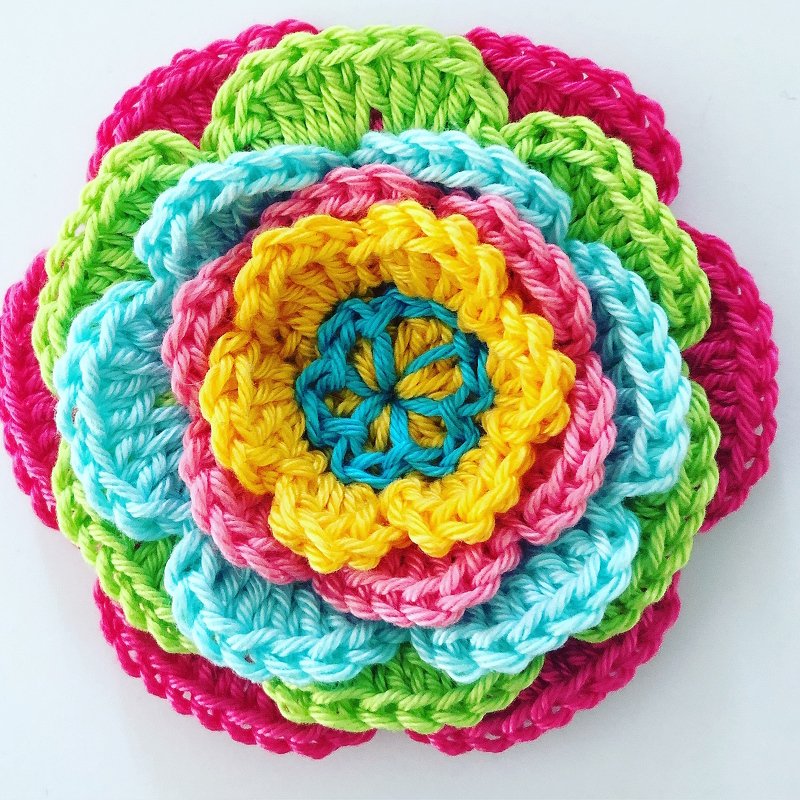 Close-up of stacked crochet flower showing stitch texture and scalloped petal layers in bright yarns