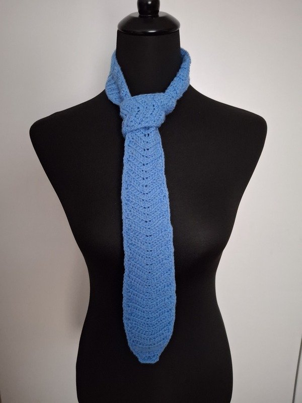 Light blue crocheted tie with chevron stitch, knotted on a black mannequin