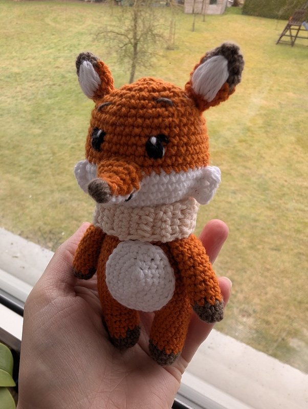 Nahaufnahme gehäkelter Amigurumi-Fuchs in Hand mit sichtbaren Maschen