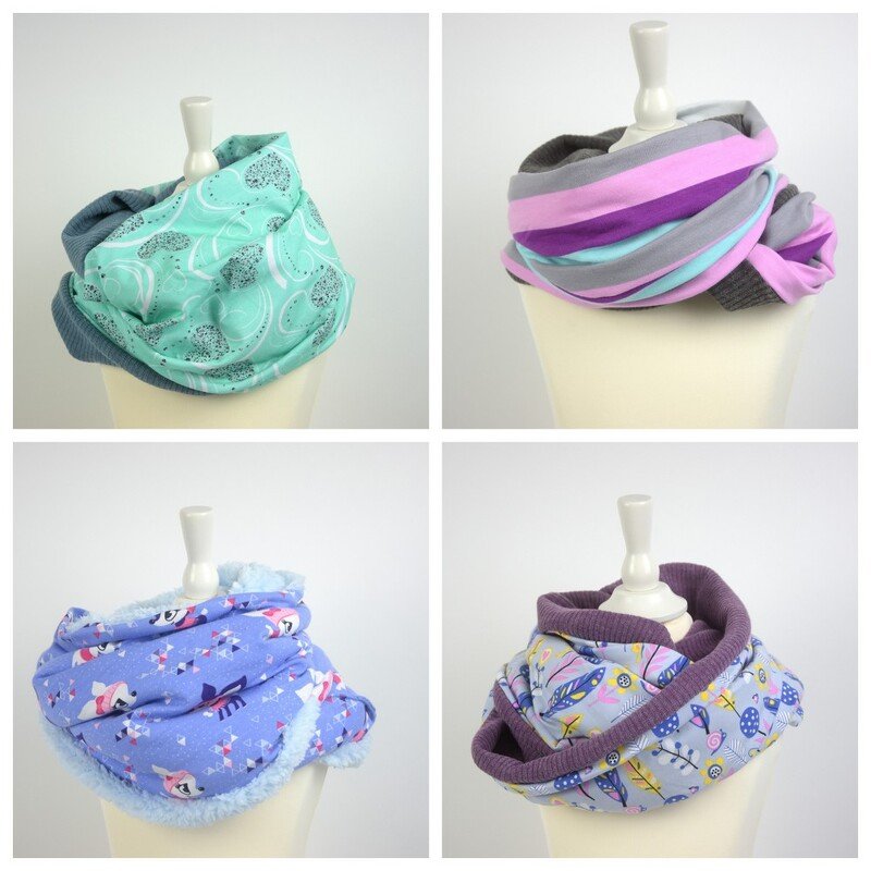 Vier Loop-Schals auf Mannequins in Mint, gestreift, mit Tiermotiv und mit Federprint.
