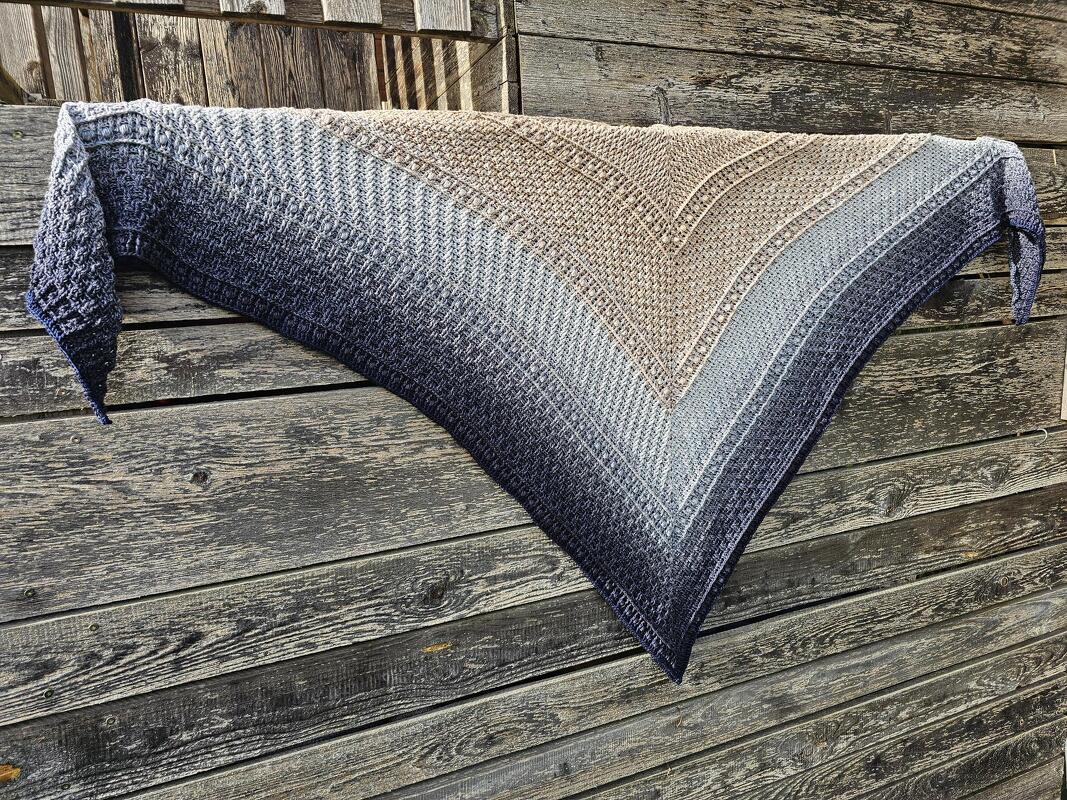 Gehäkeltes Dreieckstuch mit Farbverlauf von Beige zu Dunkelblau auf Holzplanken