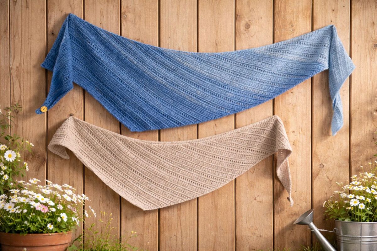 Zwei gestrickte Dreieckstücher in Blau und Beige mit diagonalen Ajour- und Rippenstreifen an einer Holzwand