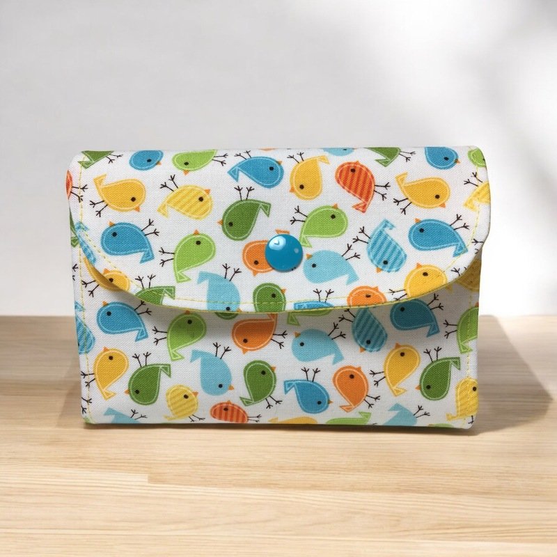 Rechteckige Utensilo-Tasche aus bedrucktem Stoff mit bunten Vögeln und blauem Druckknopf