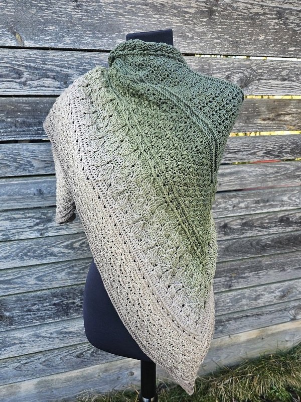 Gehäkeltes Dreieckstuch mit Grün‑zu‑Beige Farbverlauf auf schwarzer Schneiderpuppe vor Holzwand