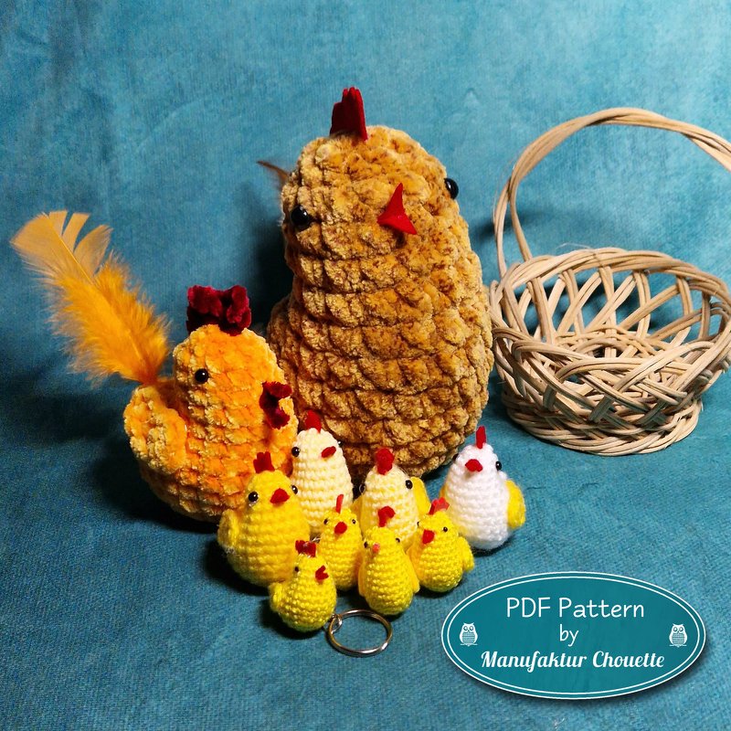 Mehrere gehäkelte gelbe und weiße Küken und Hühner in verschiedenen Größen neben einem Korb auf blauem Stoff