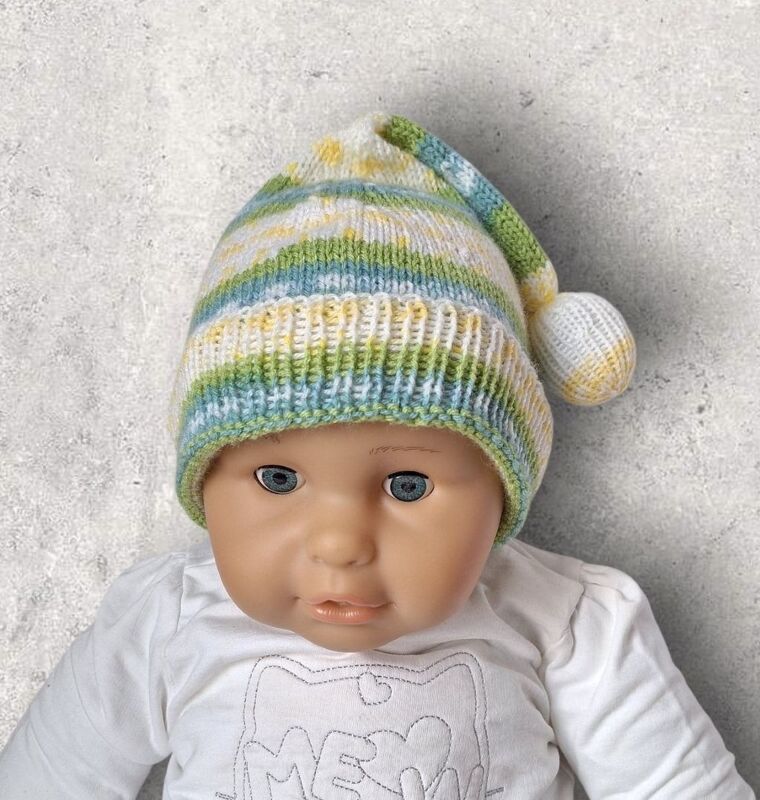 Puppe mit gestrickter Babymütze in Grün, Blau, Gelb und Weiß, mit Rippenbündchen und Zipfel samt Bommel