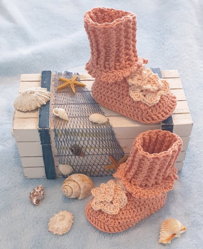 Gehäkelte pfirsichfarbene Babyschuhe mit Häkelblüte, dekoriert mit Muscheln und Seesternen