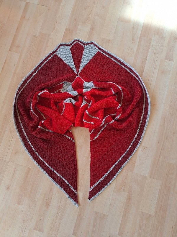 Bordeauxrotes Dreieckstuch mit hellgrauen Streifen und fächerförmigem Design auf hellem Holzboden