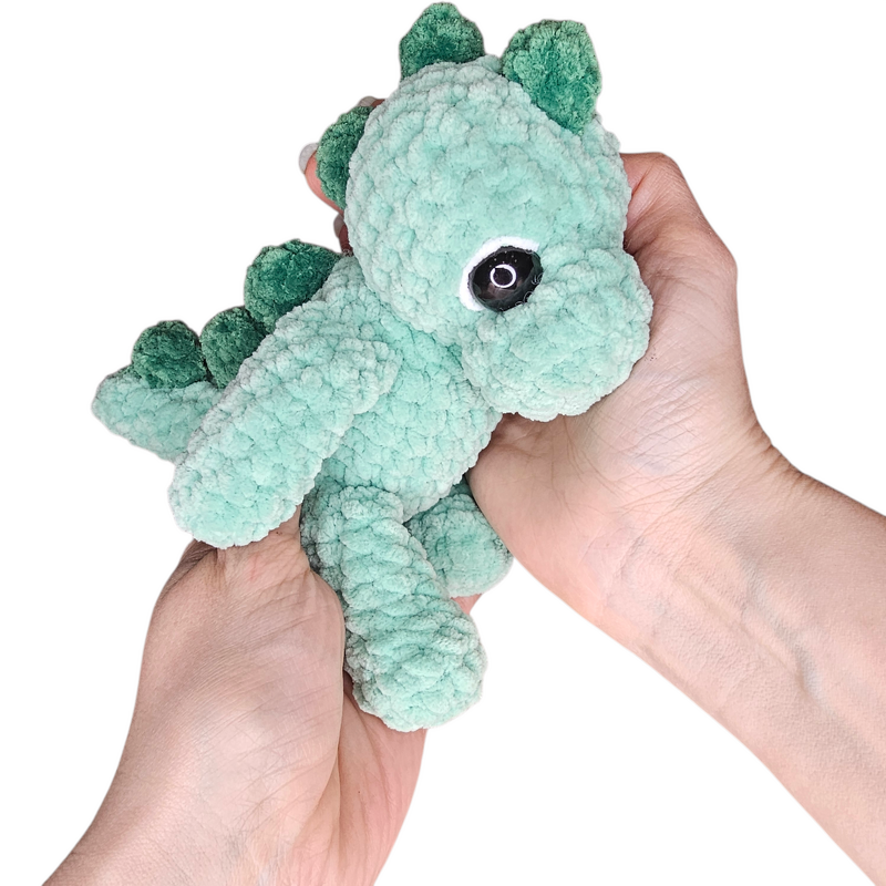 Mintgrüner gehäkelter Drache (Amigurumi) in Händen gehalten