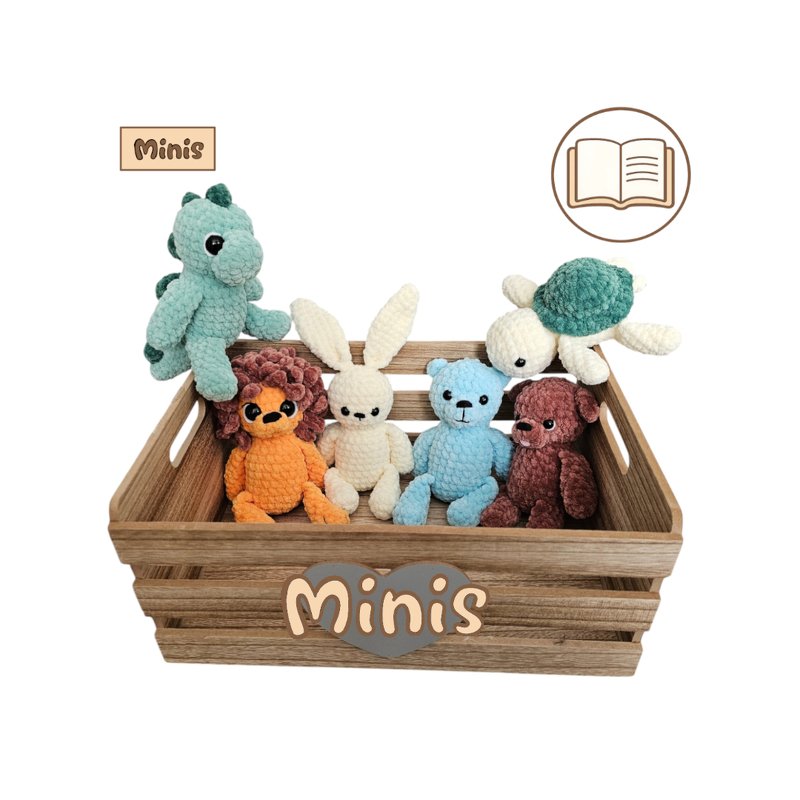Sechs gehäkelte Amigurumi‑Minis (Dino, Hase, Löwe, Schildkröte, zwei Bären) in einer Holzkiste mit Schriftzug „Minis“