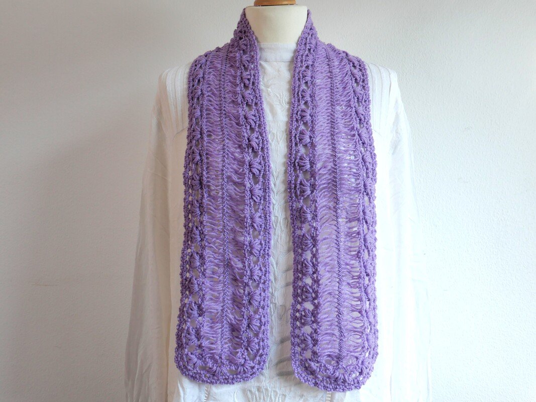 Lila gehäkelter Schal mit Lochmuster an weißer Schneiderpuppe